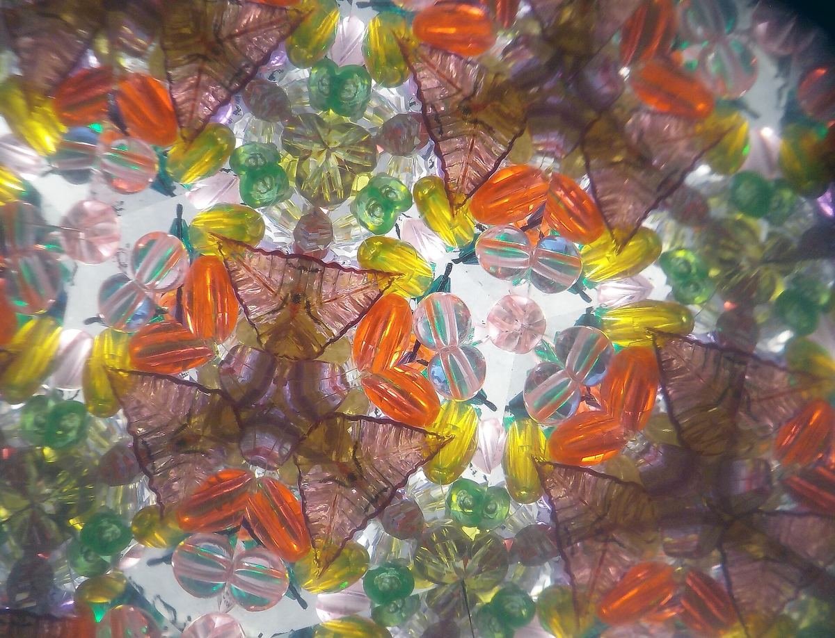 Blick in ein Kaleidoskop: Aus wenigen bunten Teilen wird ein vielfach gespiegeltes Muster.